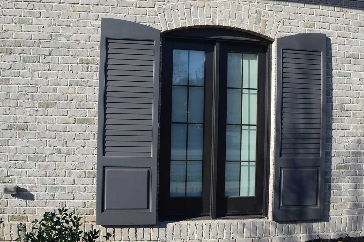 gray combination and cutout exterior shutters on white brick building