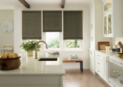 olive green woven wood roller shades on large kitchen windows in room with white accents